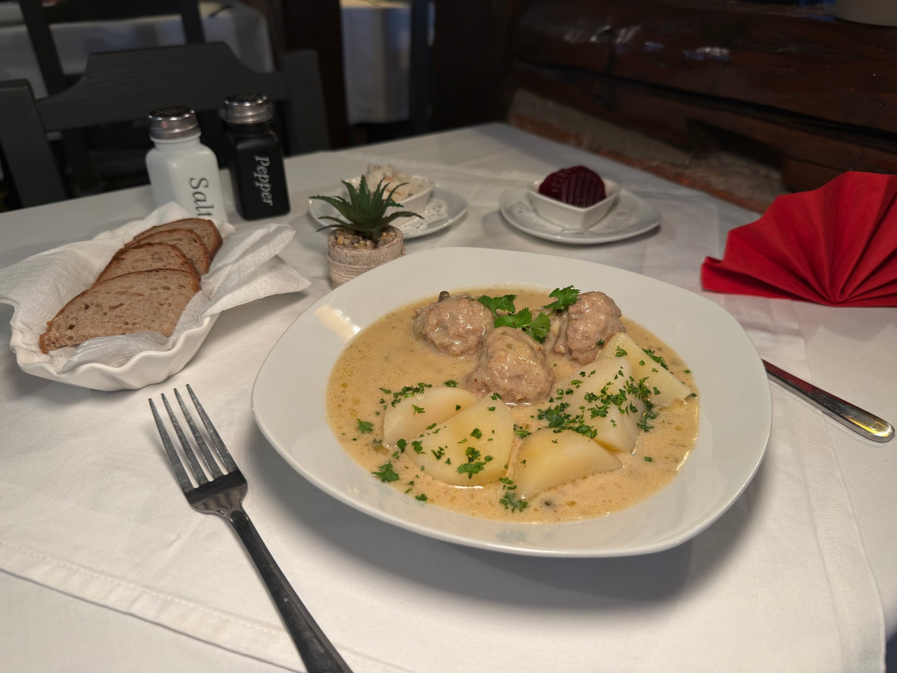 Klopse in heller Sauce mit Kartoffeln und Brotkorb